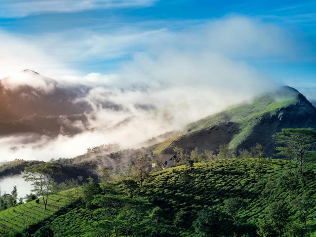 Green mountains with clouds and sun in the background